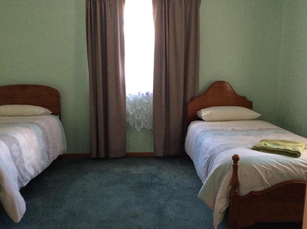 een slaapkamer met 2 bedden en een raam bij Our Cottage in Ross