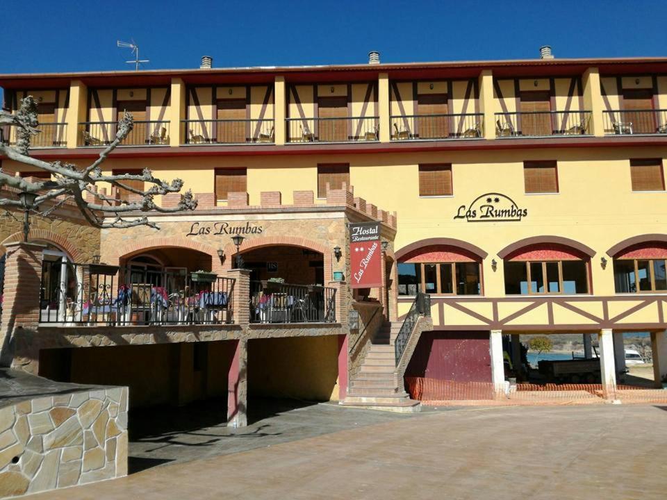 un gran edificio amarillo con balcón y escaleras en Hostal Las Rumbas, en Nuévalos