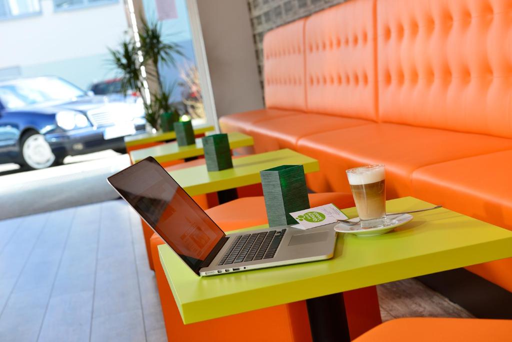 einen Laptop auf einem Tisch mit einer Tasse Bier in der Unterkunft SleepySleepy Hotel Gießen in Gießen