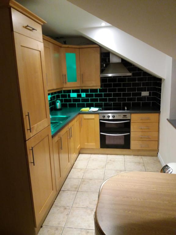 a kitchen with wooden cabinets and a stove top oven at Beautiful Seaview Penthouse Apartment in Bundoran