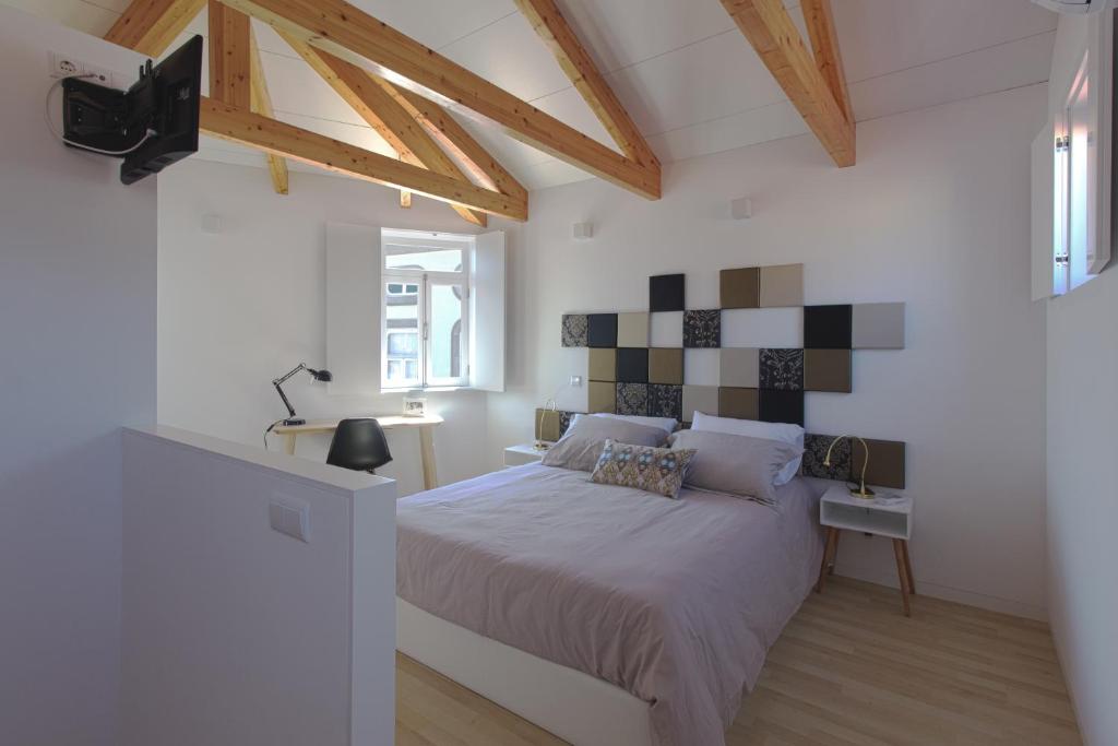 een slaapkamer met een bed in een kamer met houten plafonds bij Mordoma Guest House in Viana do Castelo