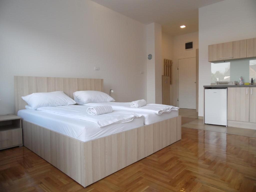 un grande letto bianco in una stanza con cucina di Apartment Subotica a Subotica