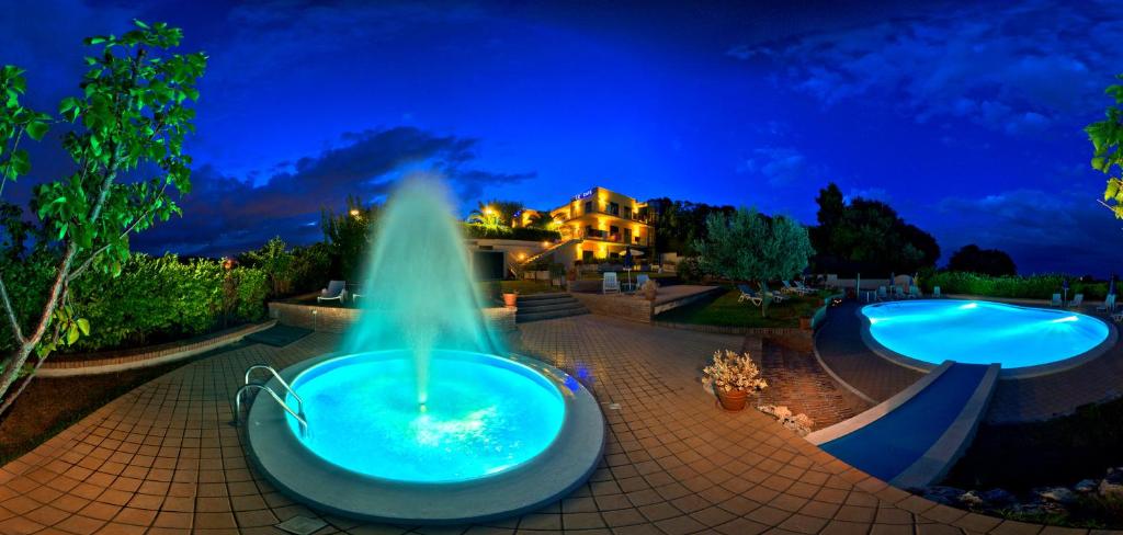 una fuente en medio de dos piscinas por la noche en Hotel Le Cave, en Sirolo