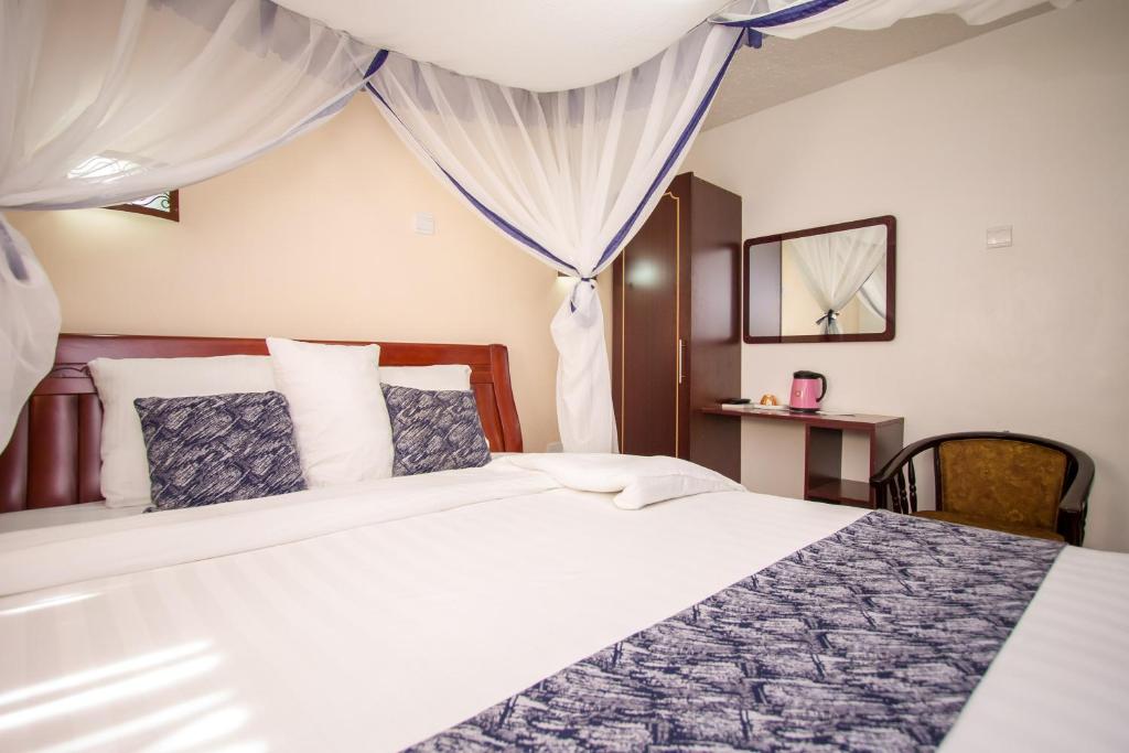 a bedroom with a large white bed with curtains at Wida Resort Kilimani in Nairobi