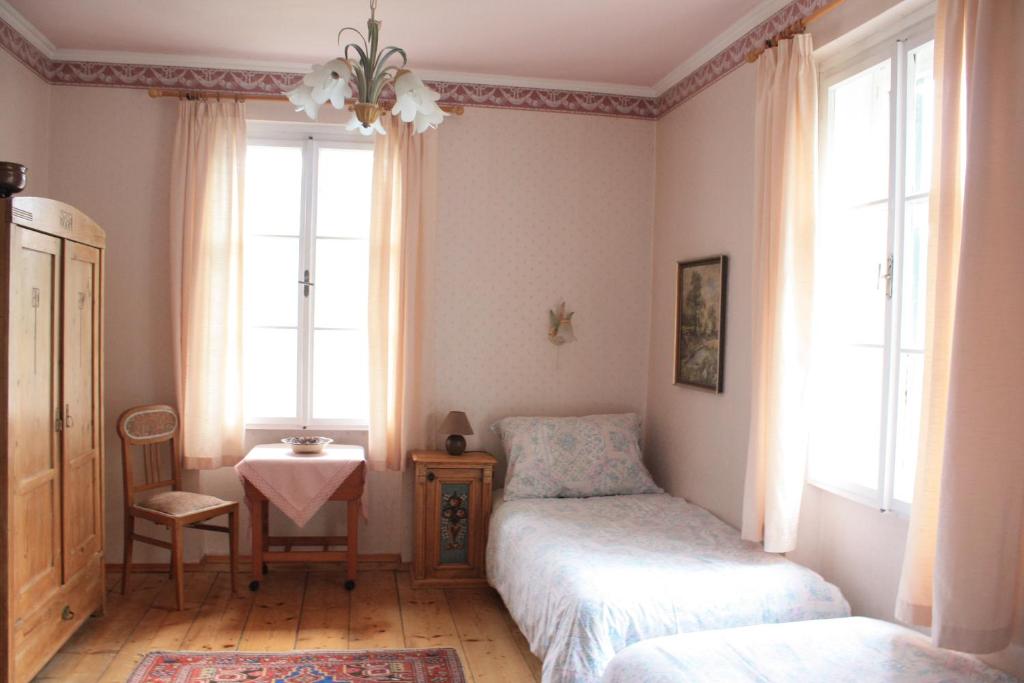 a bedroom with two beds and a table and two windows at Villa Helena in Sankt Gilgen