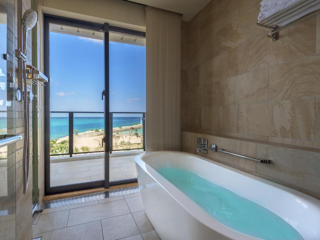 a bathroom with a tub and a view of the ocean at Sheraton Okinawa Sunmarina Resort in Onna