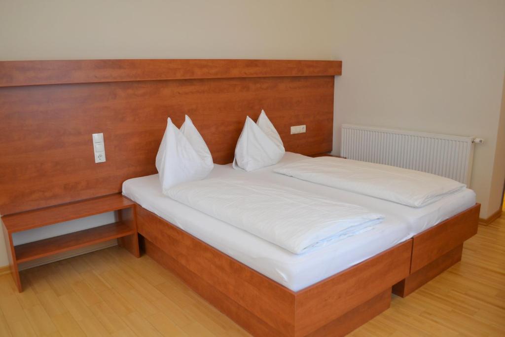 バート・グライヒェンベルクにあるHotel Grazerhofのベッド(木製ヘッドボード、白い枕付)