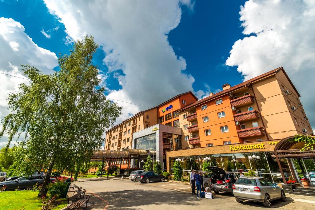 un edificio con coches estacionados en un estacionamiento en Apollo Wellness Club en Sîngeorgiu de Mureş