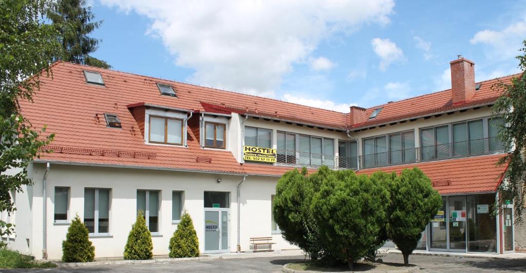 an office building with a red roof and trees at Hostel Nuove Frontiere in Nysa