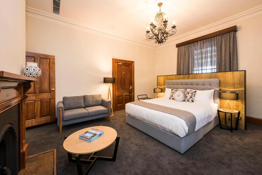a bedroom with a bed and a couch and a table at The Parkview Boutique hotel in Mudgee