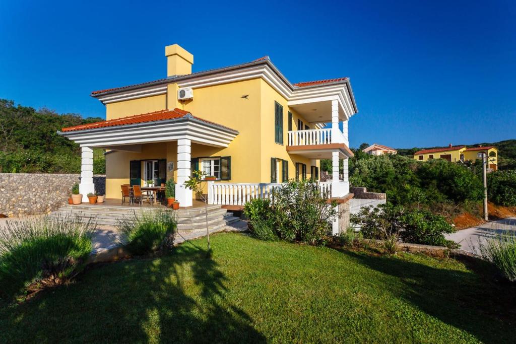 a large yellow house with a grass yard at Villa Mirela in Vrbnik