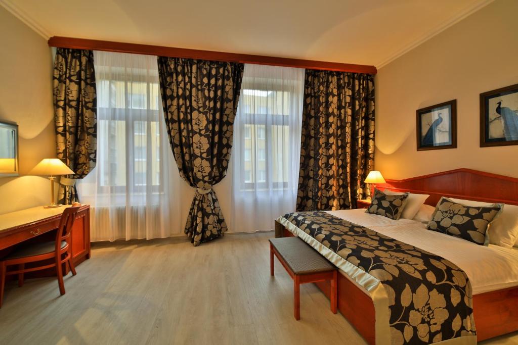 1 dormitorio con 1 cama, escritorio y ventanas en Carlton en Praga