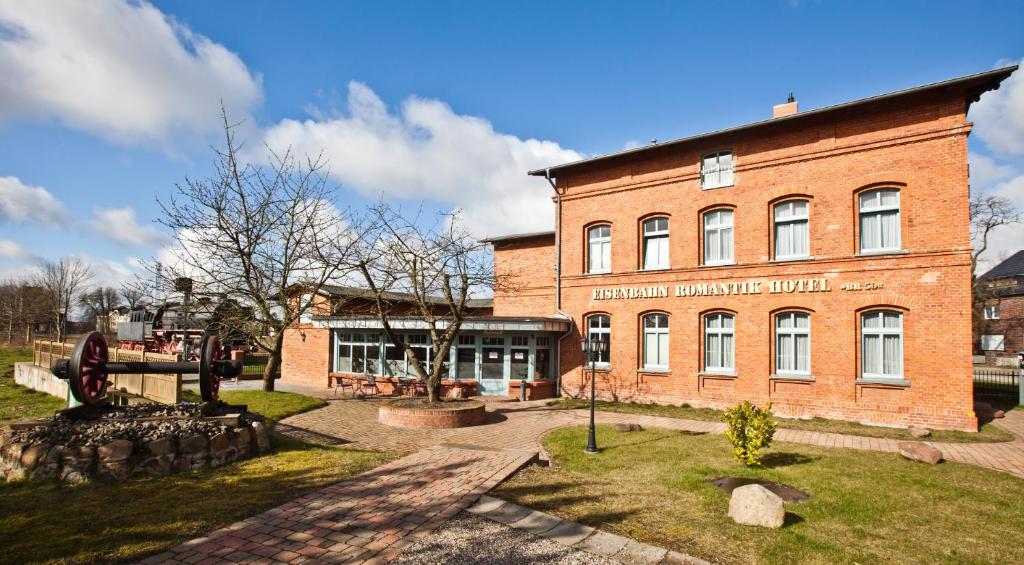 un grand bâtiment en briques devant un bâtiment dans l'établissement Eisenbahnromantik Hotel, à Meyenburg