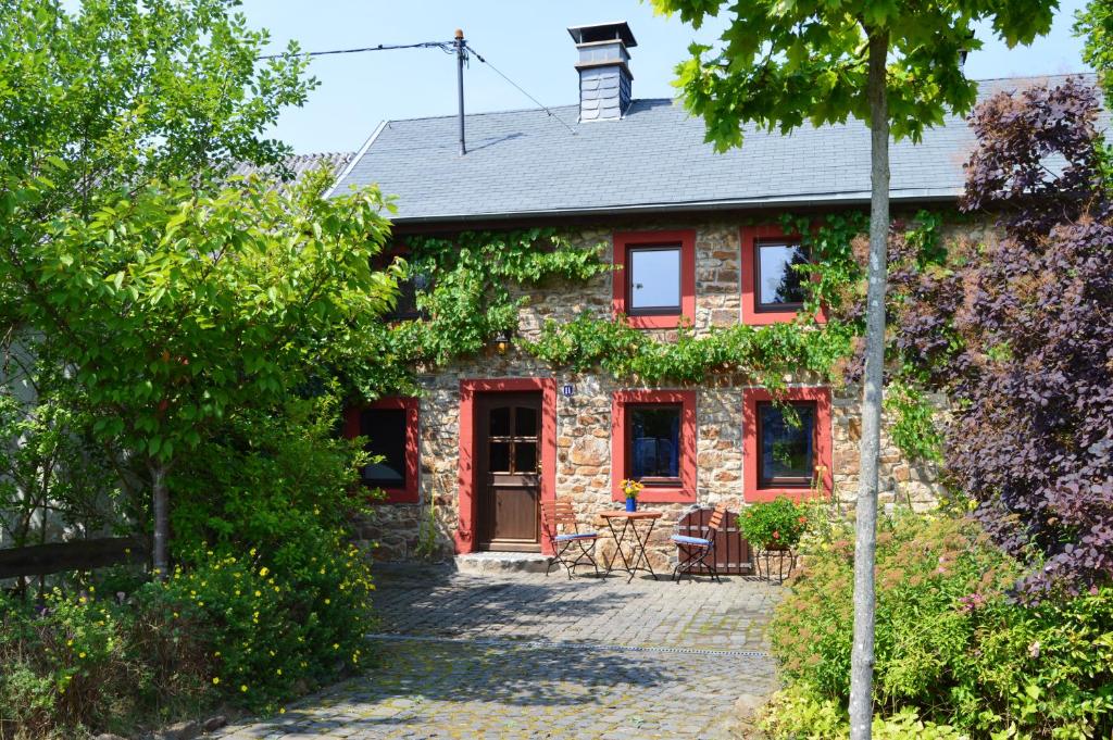ein Backsteinhaus mit einer roten Tür und einer Terrasse in der Unterkunft Haus Kaspers in Kelberg