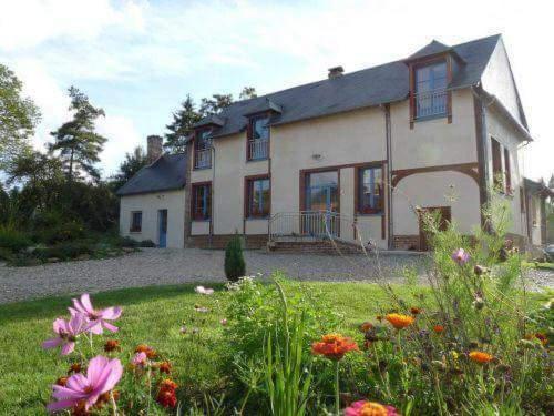 uma casa com um quintal com flores em frente em Le Moulin Aux Moines em Croissy-sur-Celle