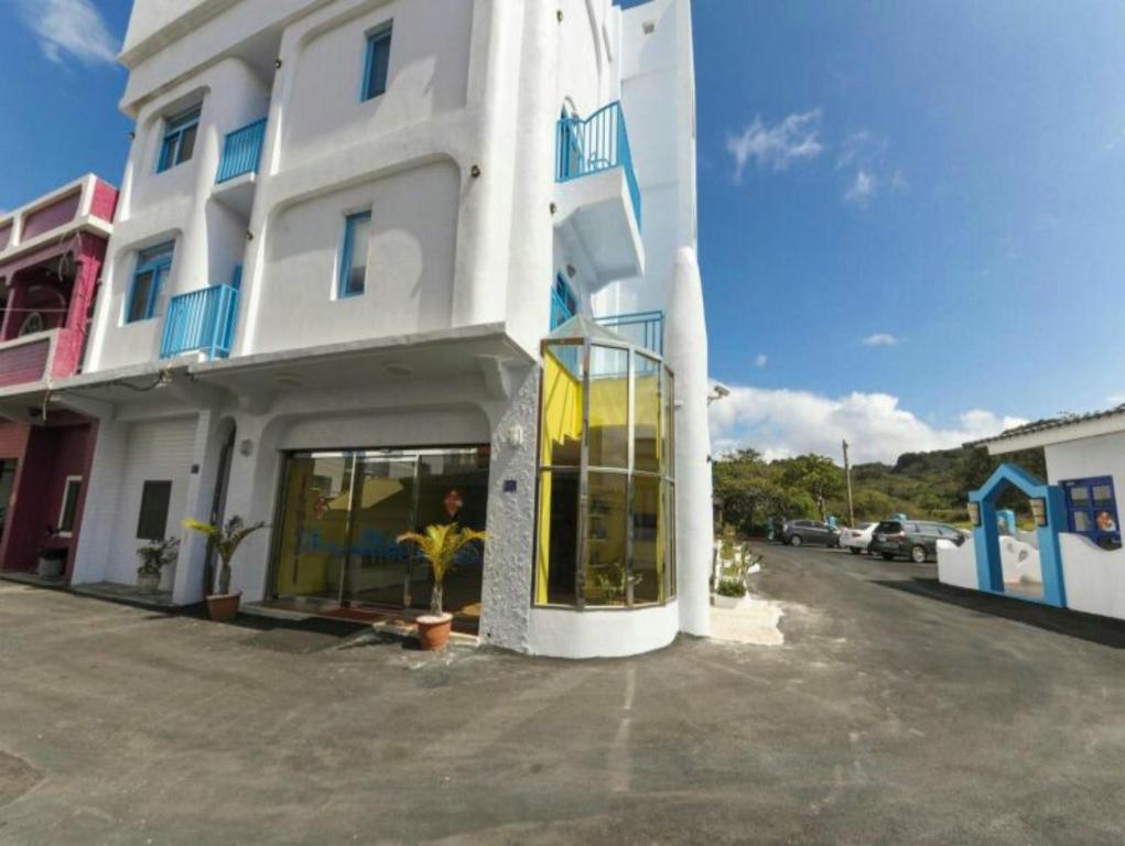 a white building with blue windows and a parking lot at Shen's Village Hotel Cozy in Eluan