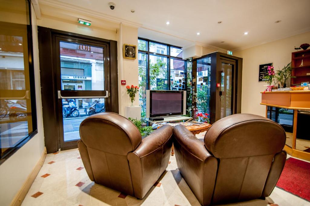 sala de estar con 2 sillas de cuero y TV en Hotel Leonard De Vinci en París