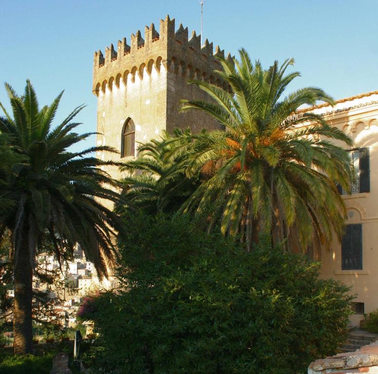 un bâtiment avec des palmiers devant un bâtiment dans l'établissement Agriturismo Castello Santa Margherita, à Cori