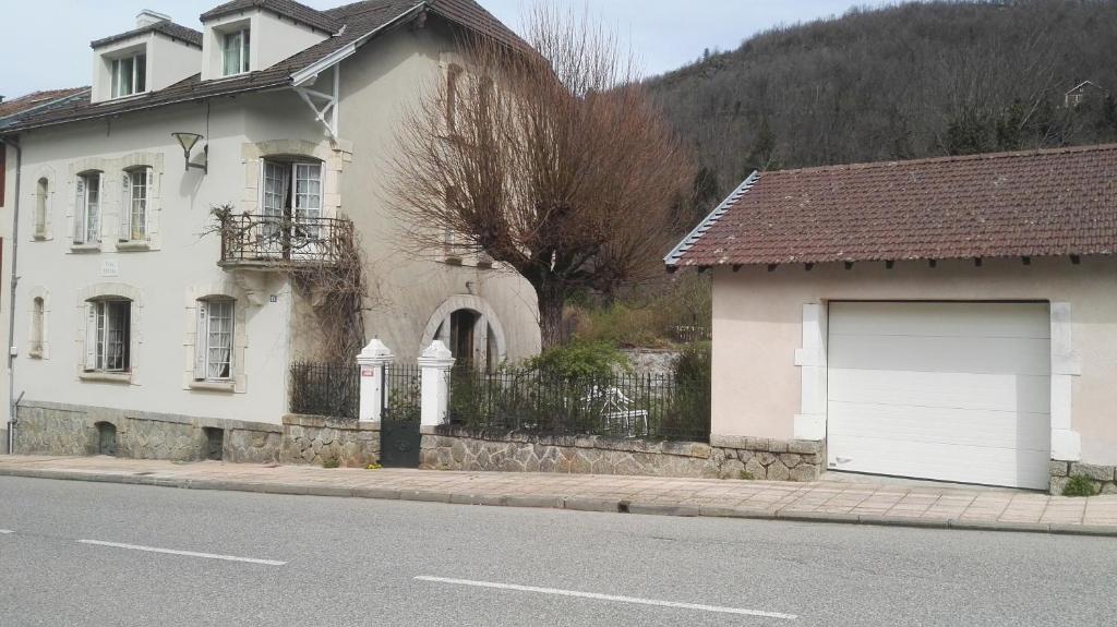a white house with a garage on the side of a street at Apartment Coecilia in Ax-les-Thermes