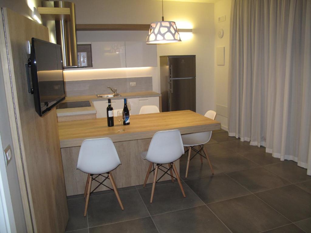 a kitchen with a wooden table and white chairs at Appartamenti Tre Colline in Bardolino