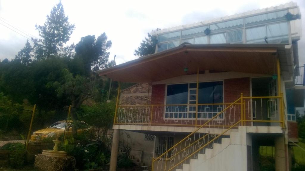 une maison avec un balcon et une voiture devant elle dans l'établissement Cabaña Los Hayuelos, à Paipa