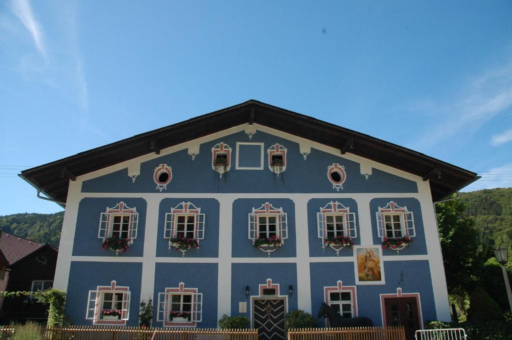 un edificio azul y blanco con ventanas y flores en Romantikhaus Hufschmiede, en Engelhartszell