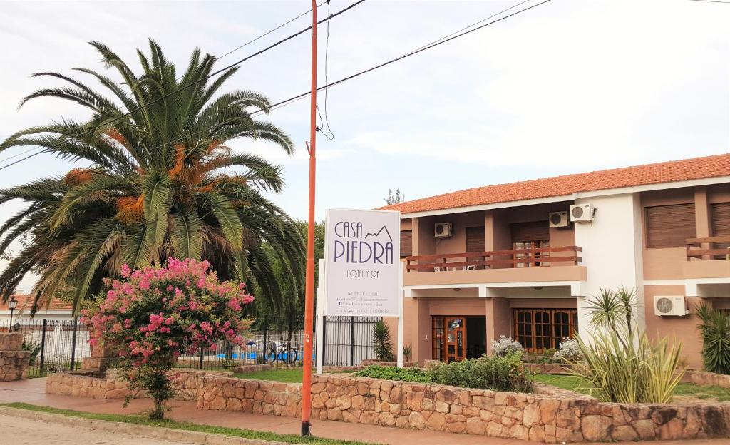 un edificio con una palmera delante de él en Casa Piedra Hotel en Villa Carlos Paz