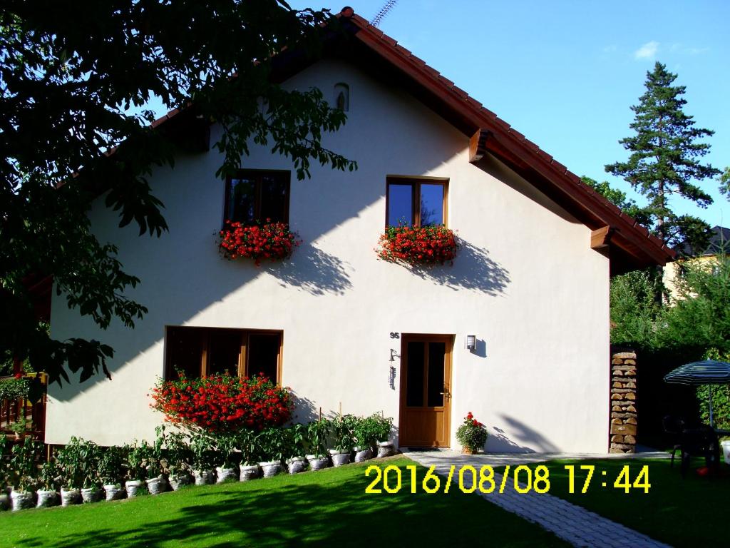 Una casa blanca con flores a un lado. en Apartmány nad Otavou, en Zvíkovské Podhradí