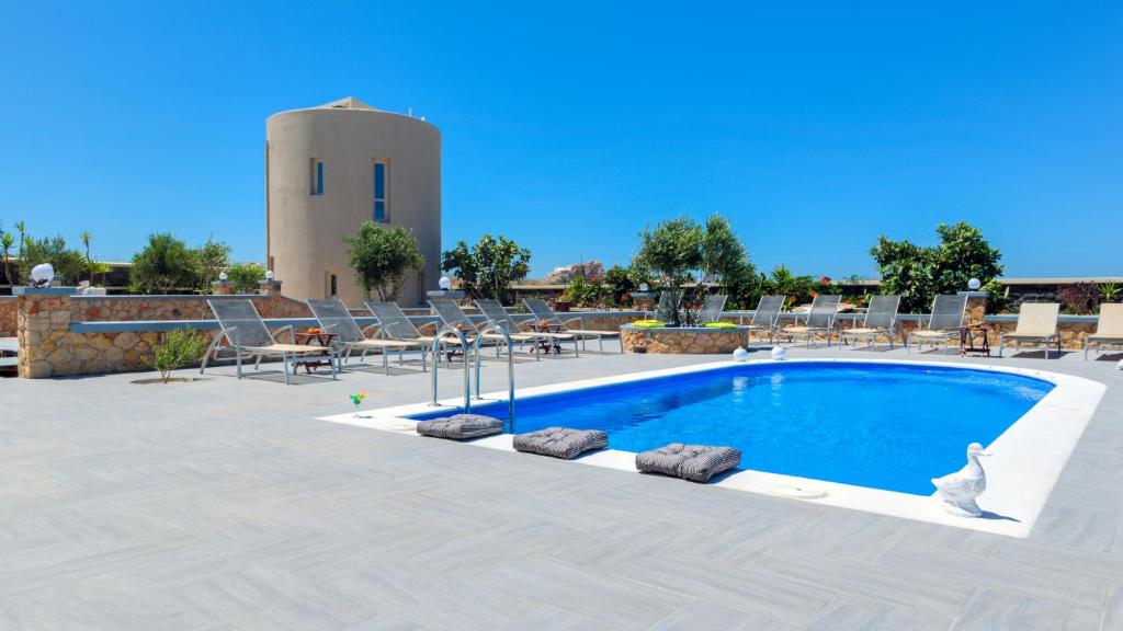 una piscina con sillas y una torre de agua en el fondo en Monolithia en Kamari