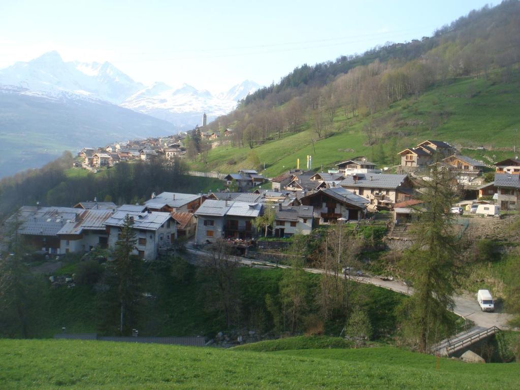 un pequeño pueblo en una colina con montañas en el fondo en La Combe de Moulin, en Peisey-Nancroix