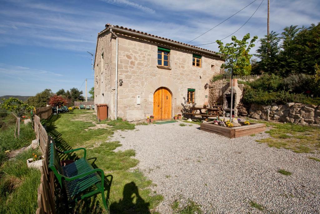 CaserrasにあるCal Viudet Vellの木の扉とベンチのある石造りの家