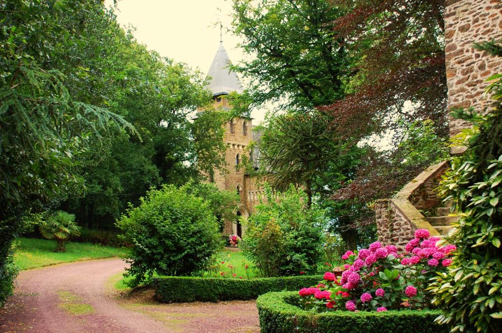 a garden with pink flowers in front of a castle at Chateau du Mur in Comblessac