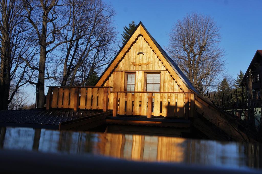 a wooden house with a fence in the water at Góralska Osada Karpacz - Apartametny in Karpacz