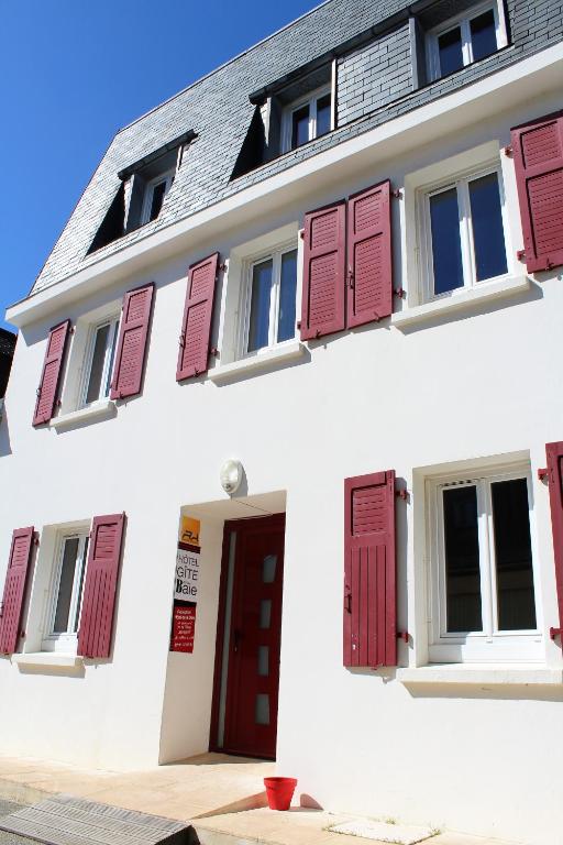 a white building with red shuttered windows and a red door at Gite de la Baie - Morgat in Crozon