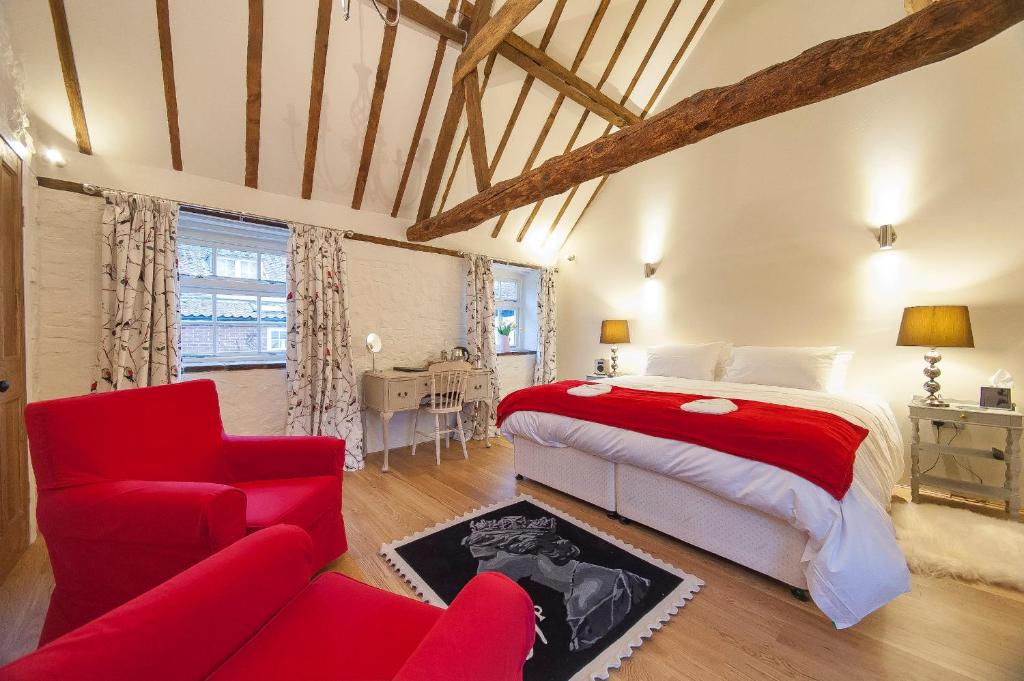 a bedroom with a red bed and a red couch at Hubbard's Luxury Bed and Breakfast in South Creake