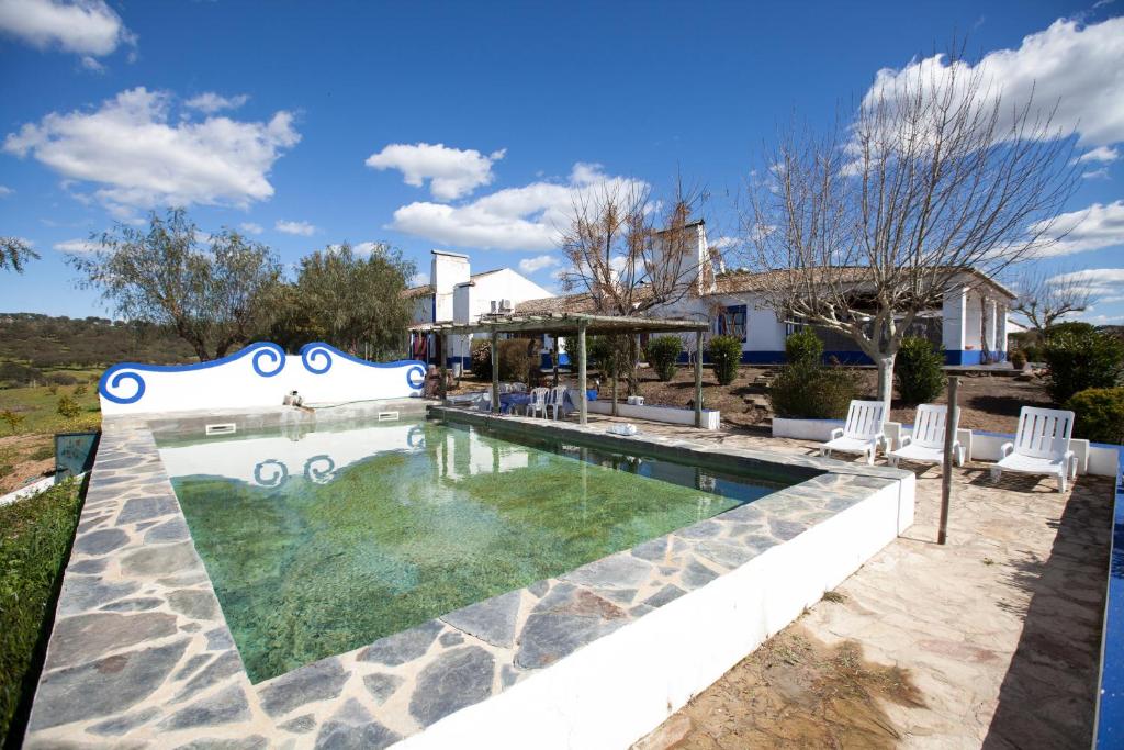 a swimming pool with chairs and a house at Herdade das Pintas in Monforte