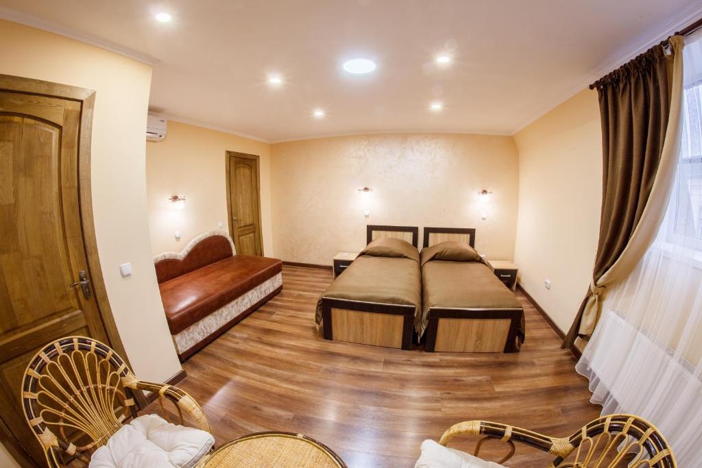Habitación de hotel con 2 camas y sofá en Panorama Apart-Hotel, en Kamianets-Podilskyi
