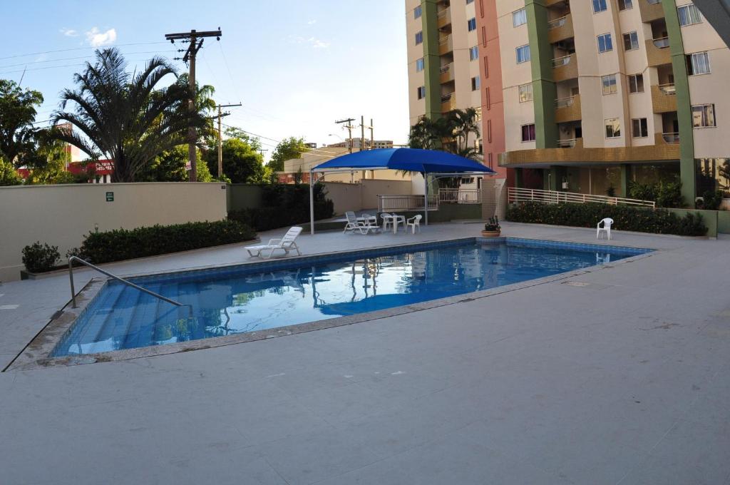 una piscina con sombrilla y sillas azules y un edificio en Vitória das Thermas - Achei Férias, en Caldas Novas