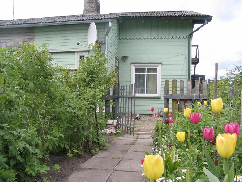 a green house with flowers in front of it at Frendlen Metsa Apartment in Pärnu