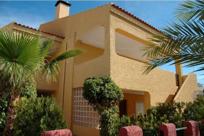 une maison avec un palmier en face dans l'établissement Apartamentos Taravilla P26, à Puerto de Mazarrón