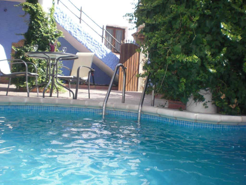 a swimming pool with a table and chairs and stairs at Apartamentos Jaronil in Benaocaz