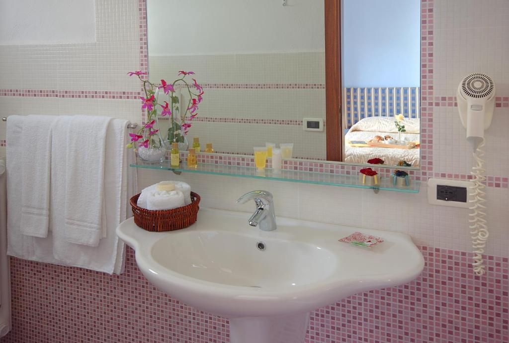 a bathroom with a sink and a mirror and towels at Iris Hotel in Ischia