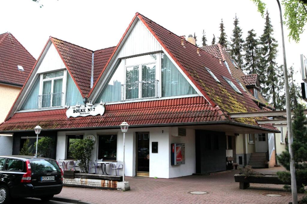 a building with a red roof with a car parked in front at Hotel Bölke in Wunstorf