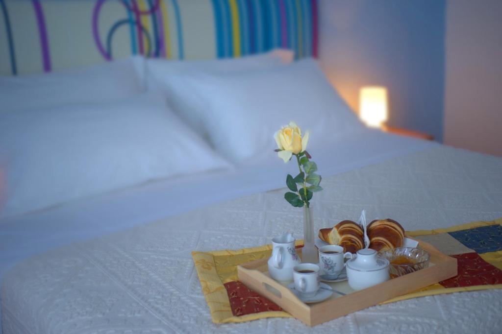 a tray with croissants and cups and a flower on a bed at Iris Hotel in Ischia