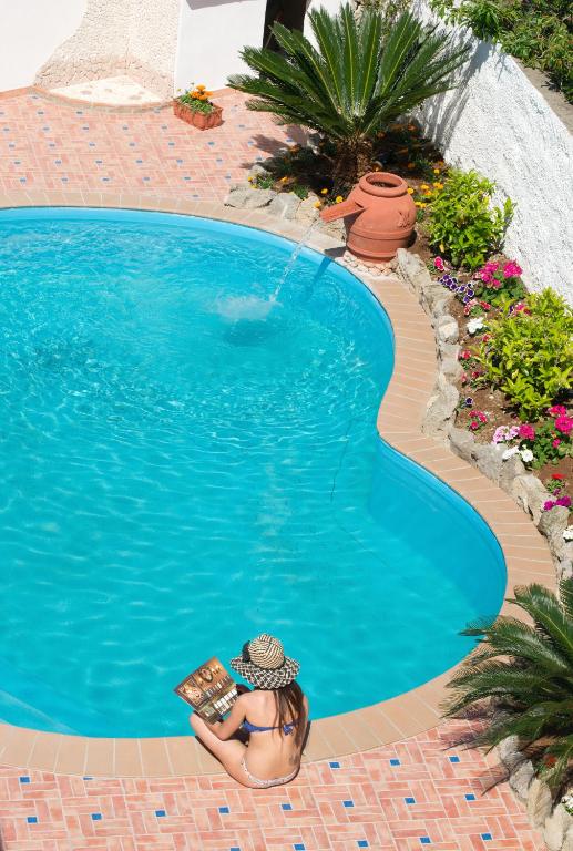 a woman reading a book in a swimming pool at Iris Hotel in Ischia