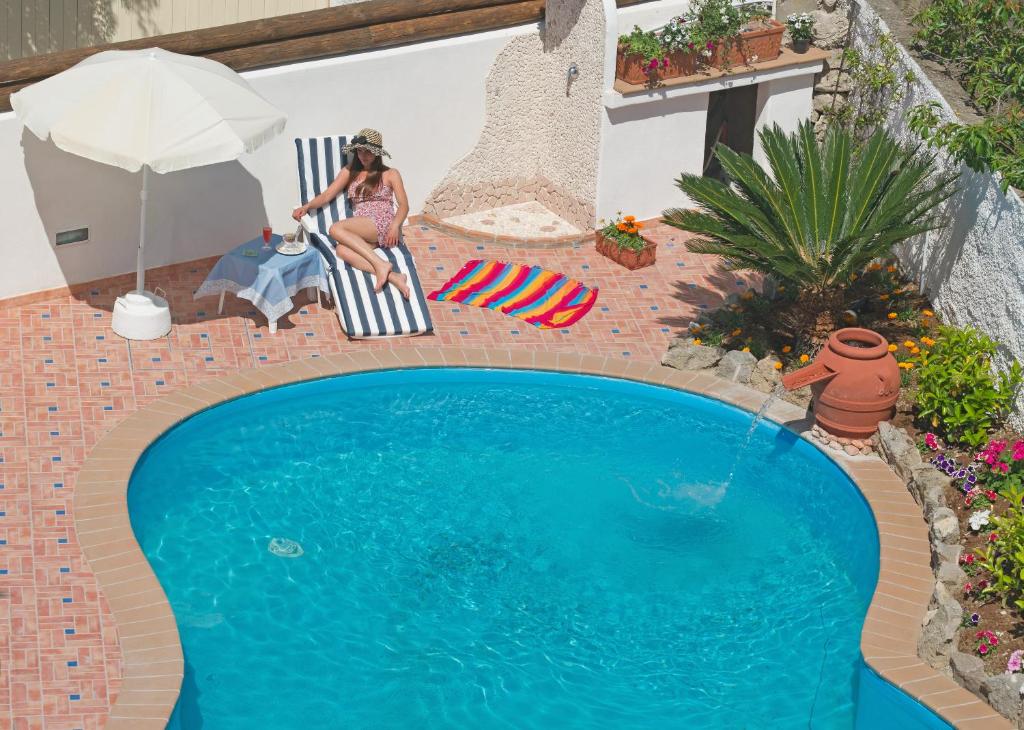 a woman sitting in a chair next to a swimming pool at Iris Hotel in Ischia
