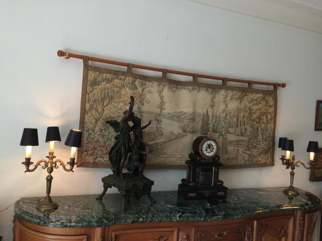 un tapiz colgado en una pared sobre una mesa con una estatua en Villa Eden, en Menton