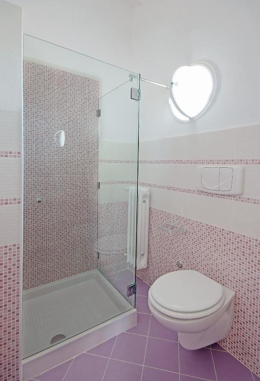 a pink bathroom with a toilet and a shower at Iris Hotel in Ischia