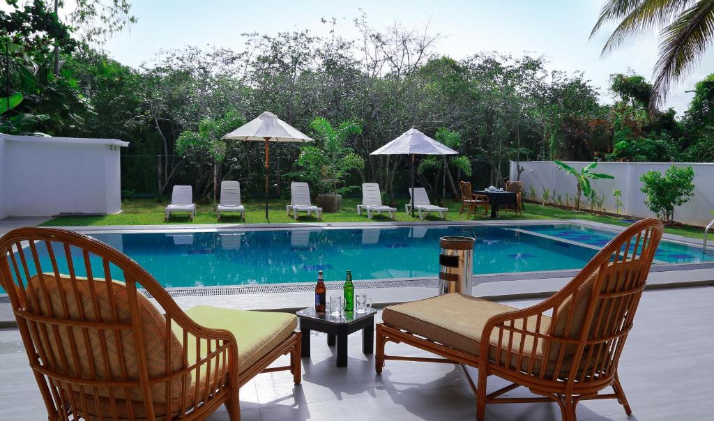 a pool with two chairs and a table with bottles of wine at Hikka Nature Villa in Hikkaduwa