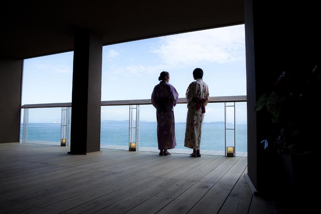 two people standing on a balcony looking out at the ocean at Hanagoyomi in Sumoto